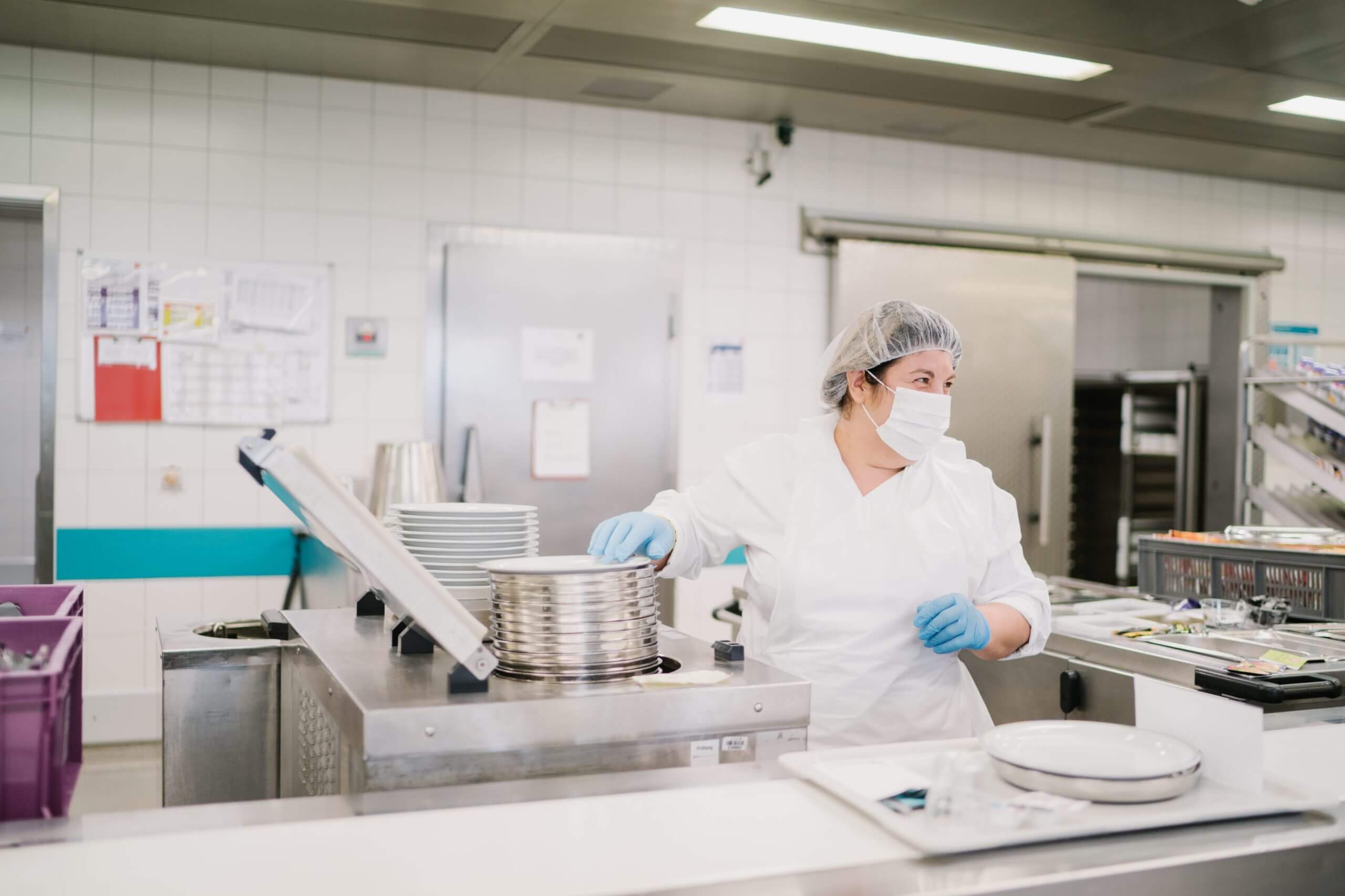 Distribution des repas en hôpital. Préparation avant livraison par une collaboratrice.